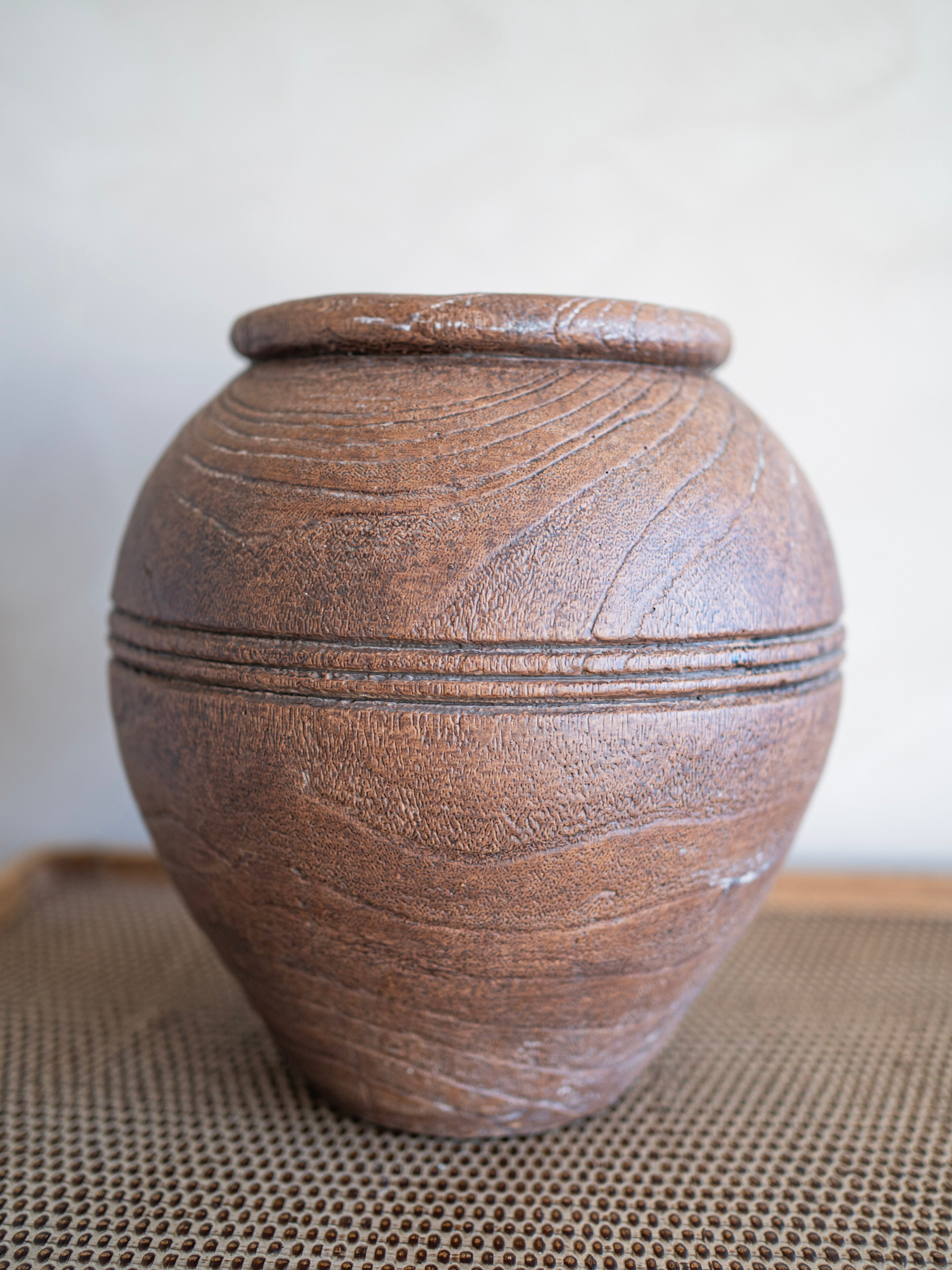 Brown ceramic vase with textured surface on a neutral background