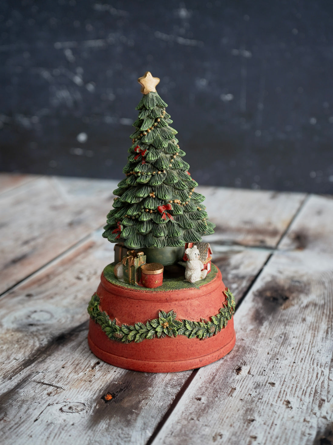 Decorative Christmas tree figurine on a wooden surface with a dark background
