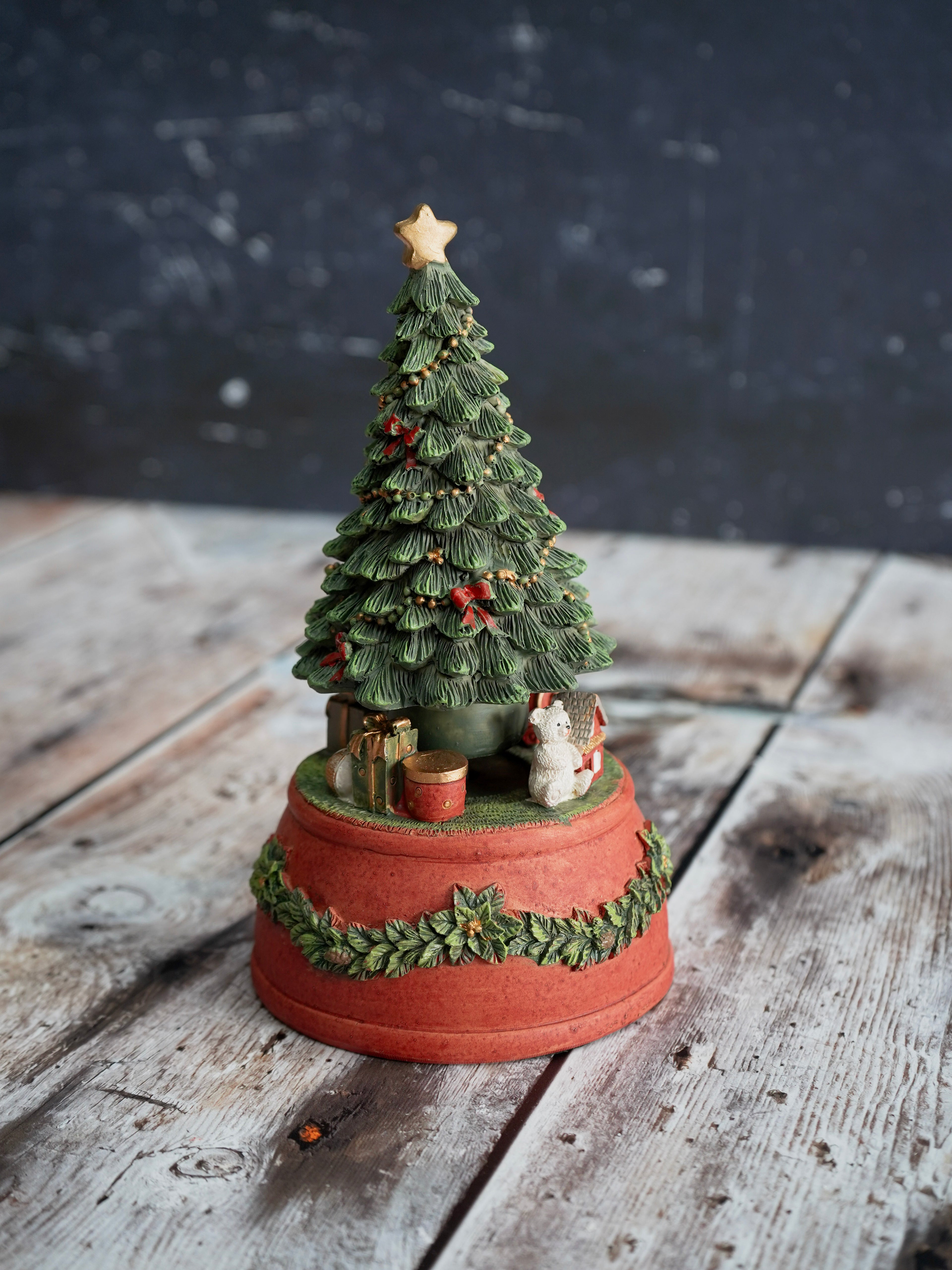 Decorative Christmas tree figurine on a wooden surface with a dark background