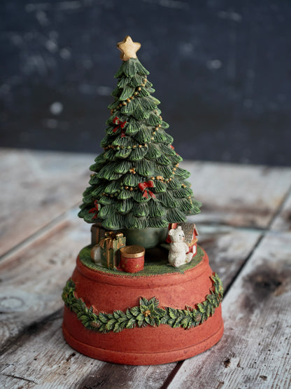 Decorative Christmas tree figurine on a wooden surface with a dark background