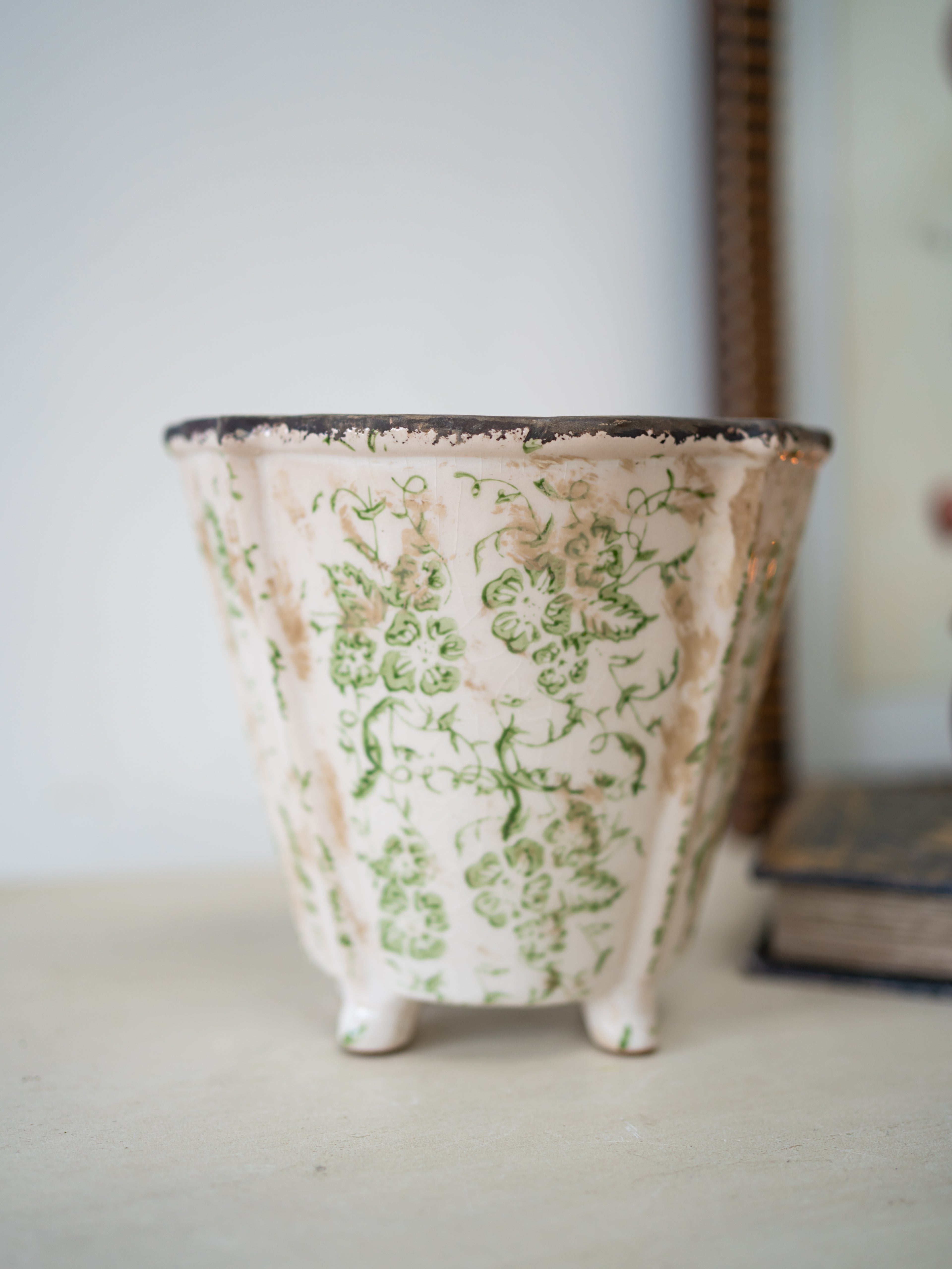 Ceramic planter with green floral pattern on a neutral background