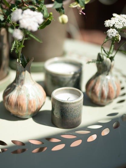 Ceramic containers with candles and flowers on a decorative table