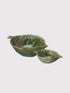 Two green ceramic leaf-shaped bowls on a light gray background