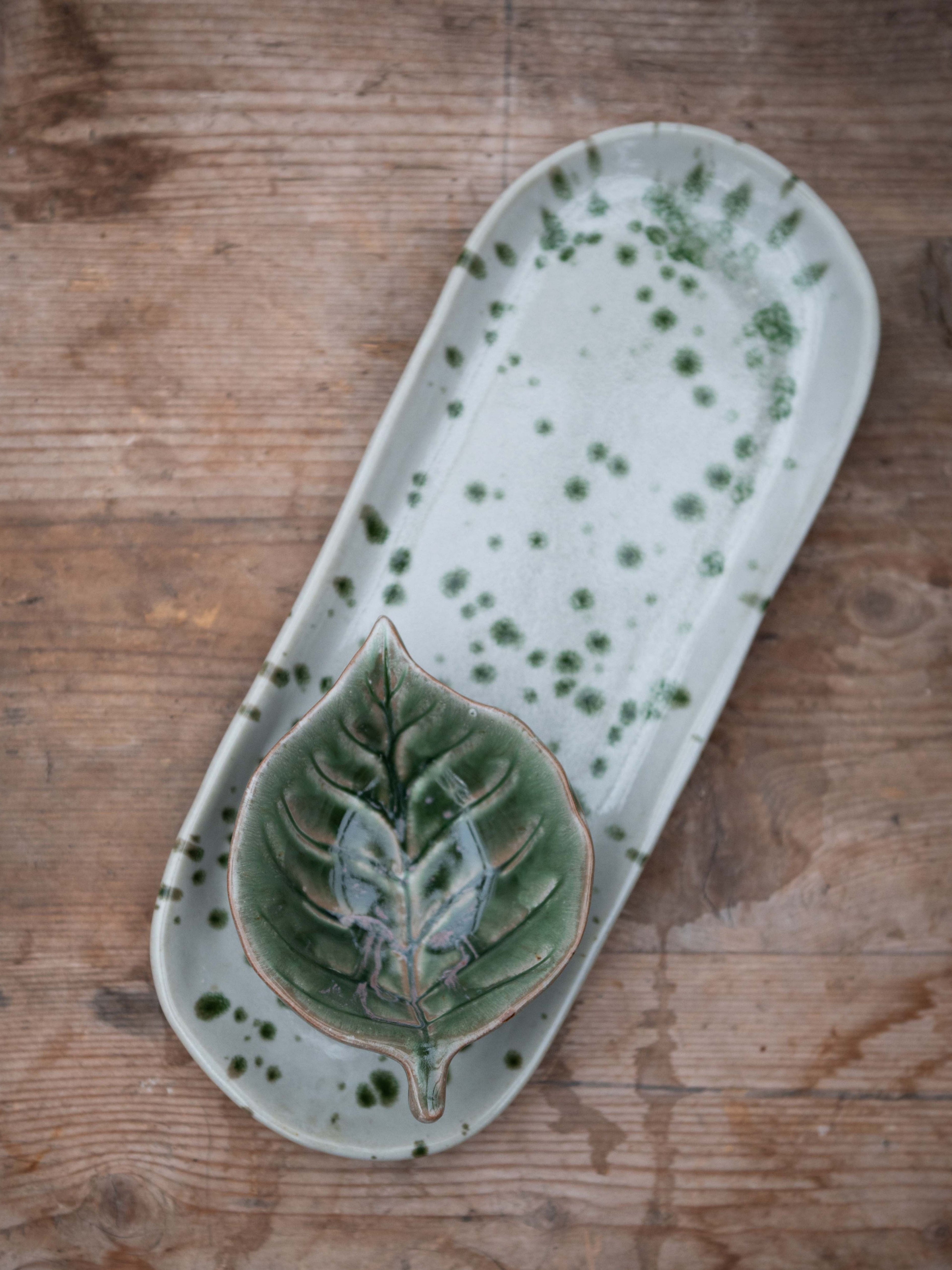 Ceramic tray with leaf design on a wooden surface
