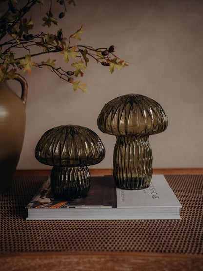 Two ribbed mushroom-shaped glass led table lamps in a smoky translucent brown color, displayed on a stack of books on a woven mat.