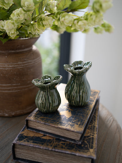 Two green ceramic vases on a stack of books with a blurred background