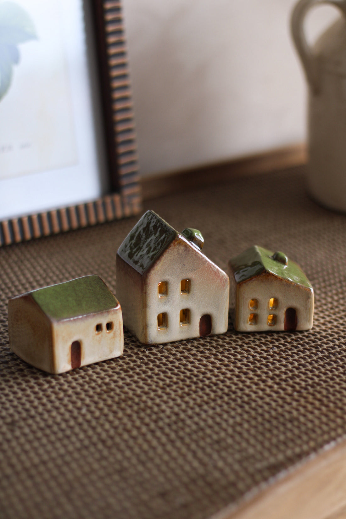 Three small ceramic houses on a textured surface with a blurred background