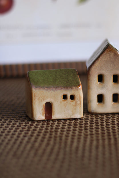 Two small ceramic houses on a textured surface with a blurred background