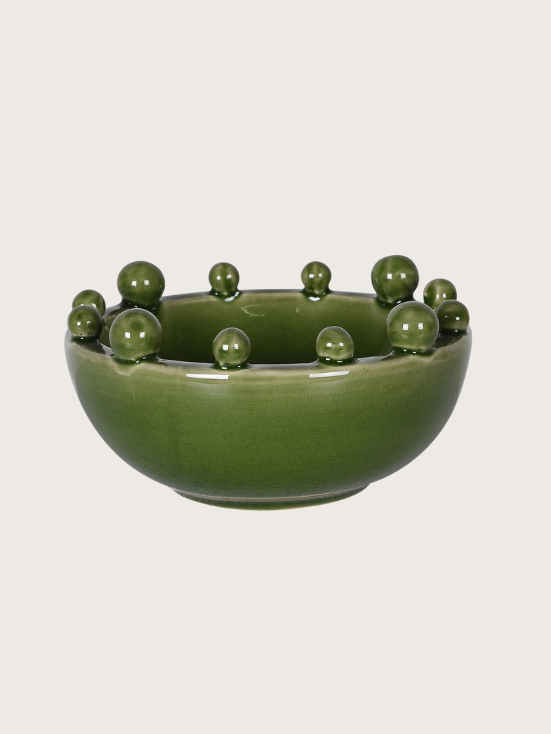 Green ceramic bowl with spherical bobbles on a light gray background