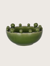 Green ceramic bowl with spherical bobbles on a light gray background