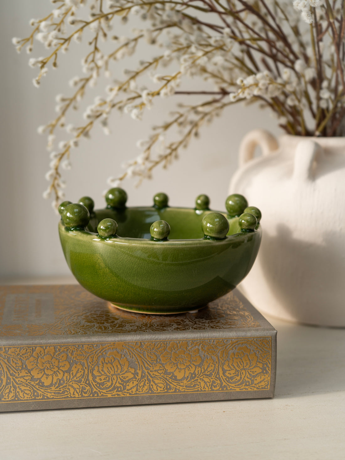 Green ceramic bowl with decorative elements on a surface with a blurred background
