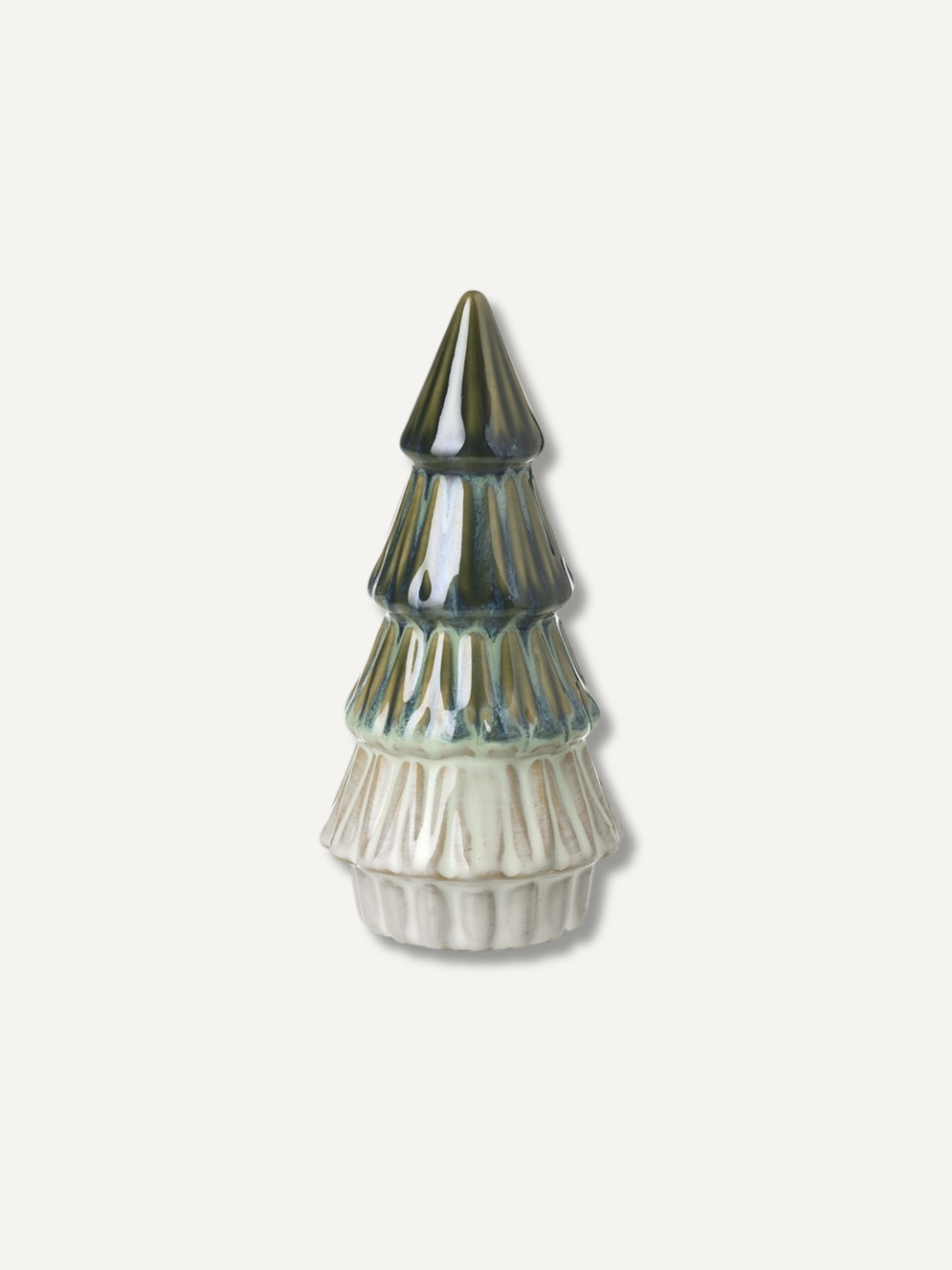 A large ceramic Christmas tree ornament with a glossy dark green and blue glazed top and a textured off-white fluted base, centered on a light beige background.