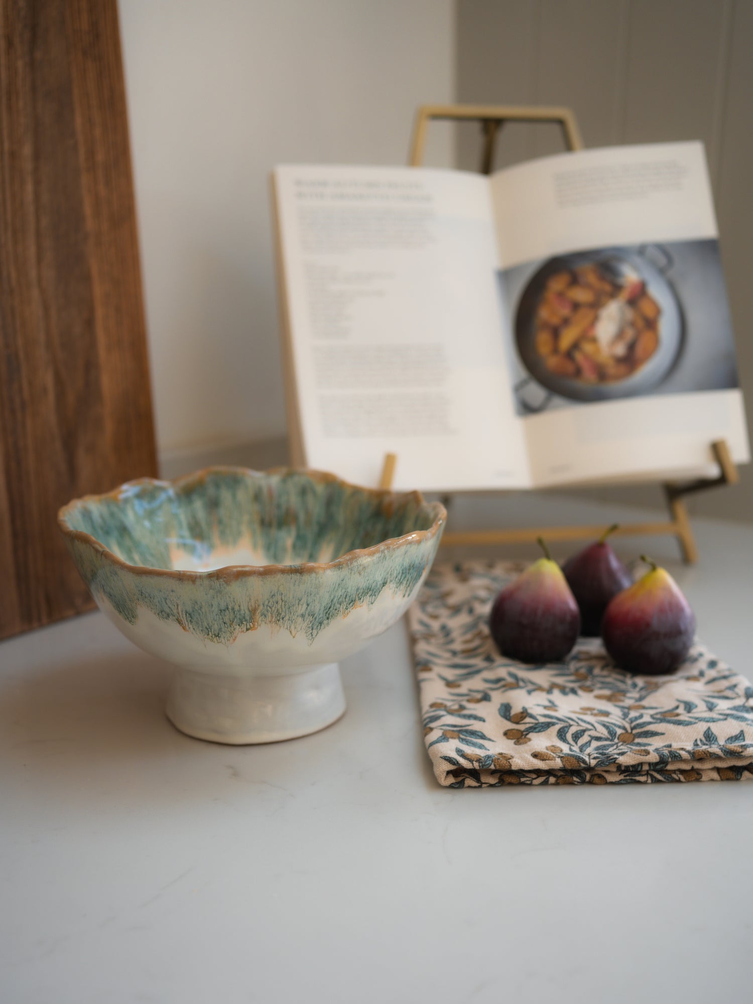 Green ombre ceramic bowl on a table with a book and fruit in the background for kitchen styling inspiration