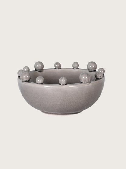 Gray ceramic bowl with bobble protrusions on a light gray background