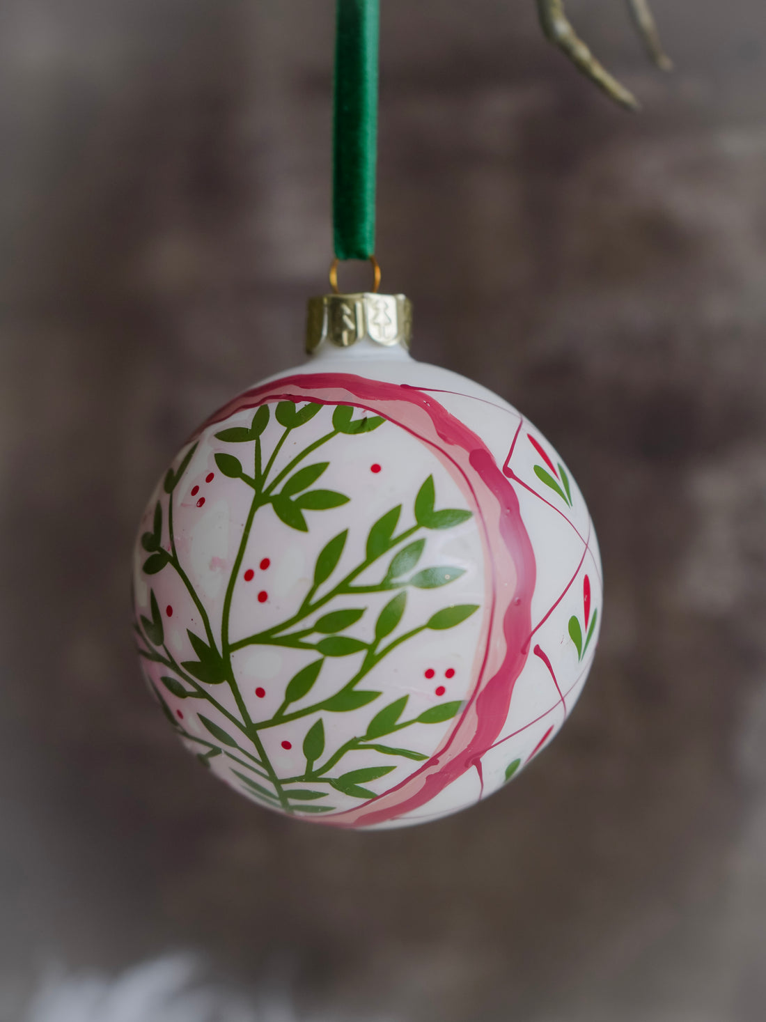Decorative Christmas ball ornament with green leaf pattern on a blurred background