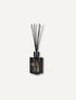 A reed diffuser with a dark glass bottle and black reeds, centered on a light off-white background.