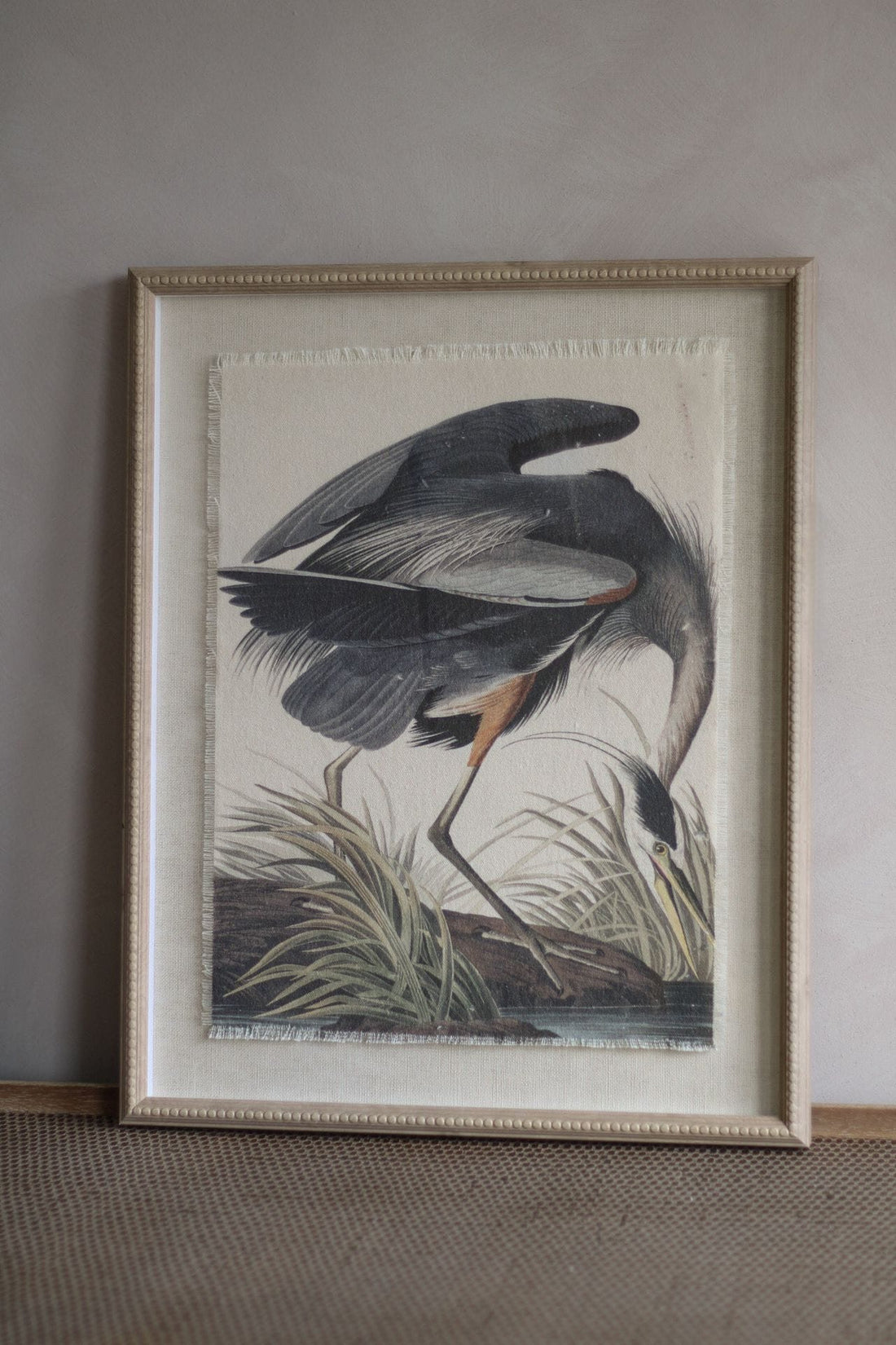 Framed artwork of a bird in a natural setting on a neutral wall.