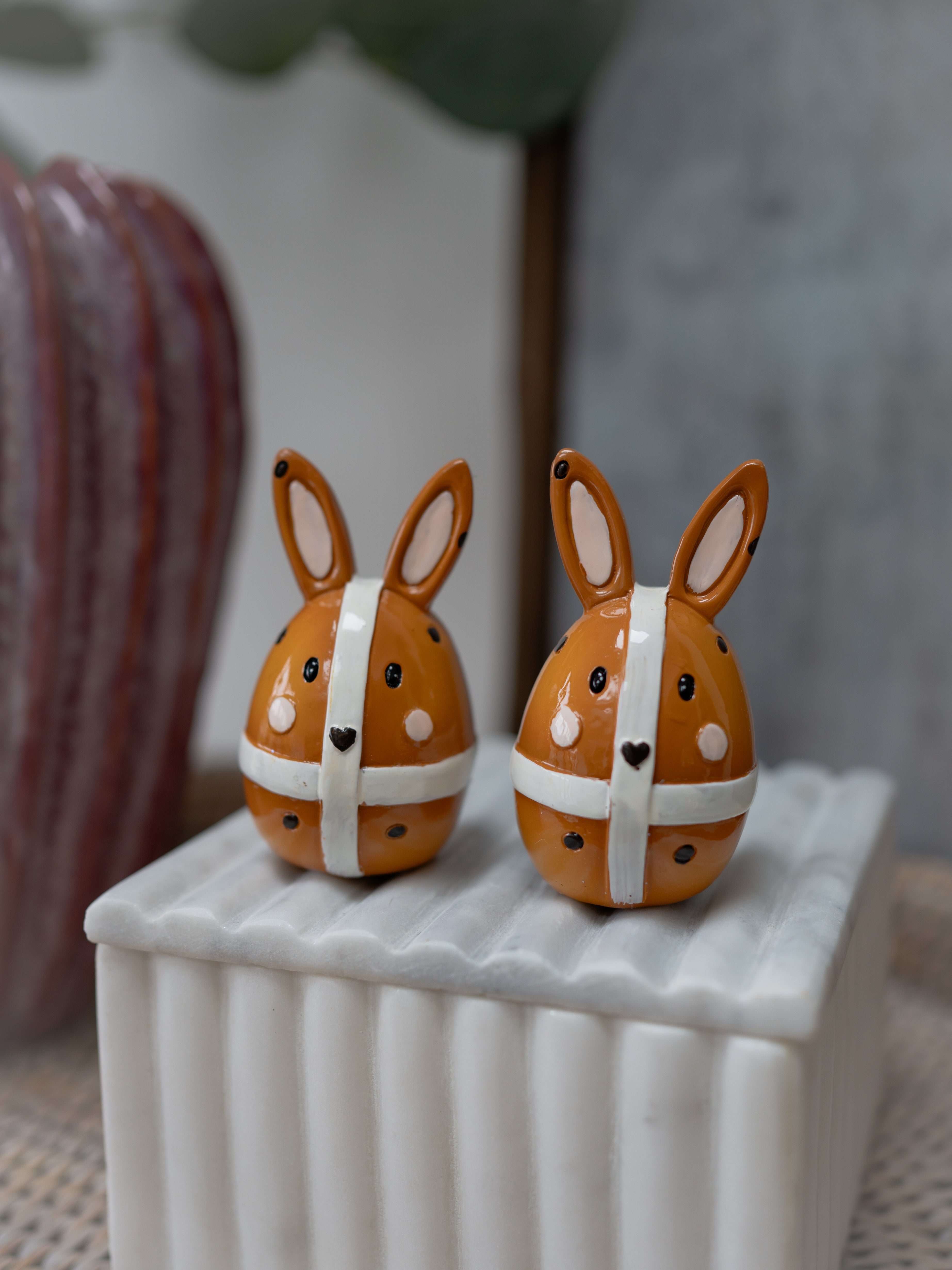 Two decorative bunny figurines with polka dot ribbons on a white surface.