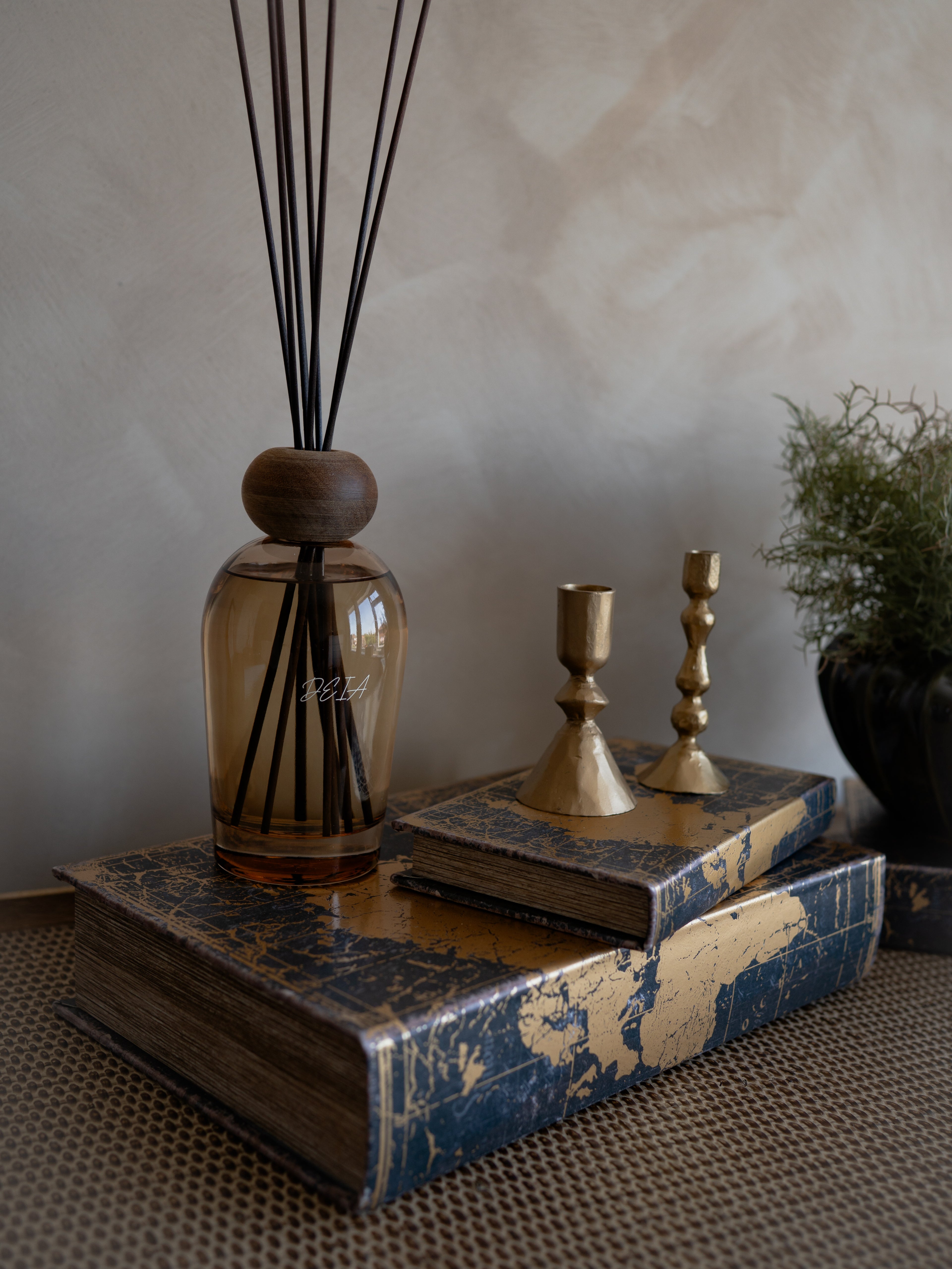 Decorative items including a diffuser, books, and candle holders on a textured surface.