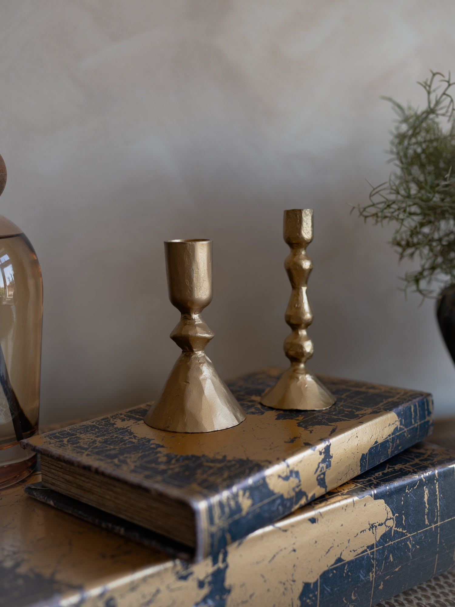 Two gold candle holders on a blue textured surface with a neutral background