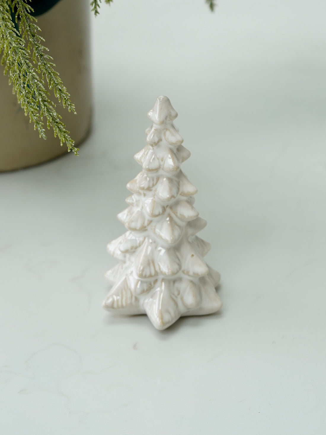 White ceramic Christmas tree ornament on a light gray background