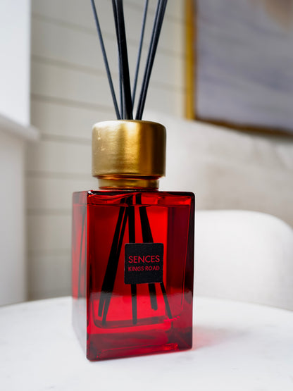 Red kings road sences diffuser bottle with gold cap on a white surface