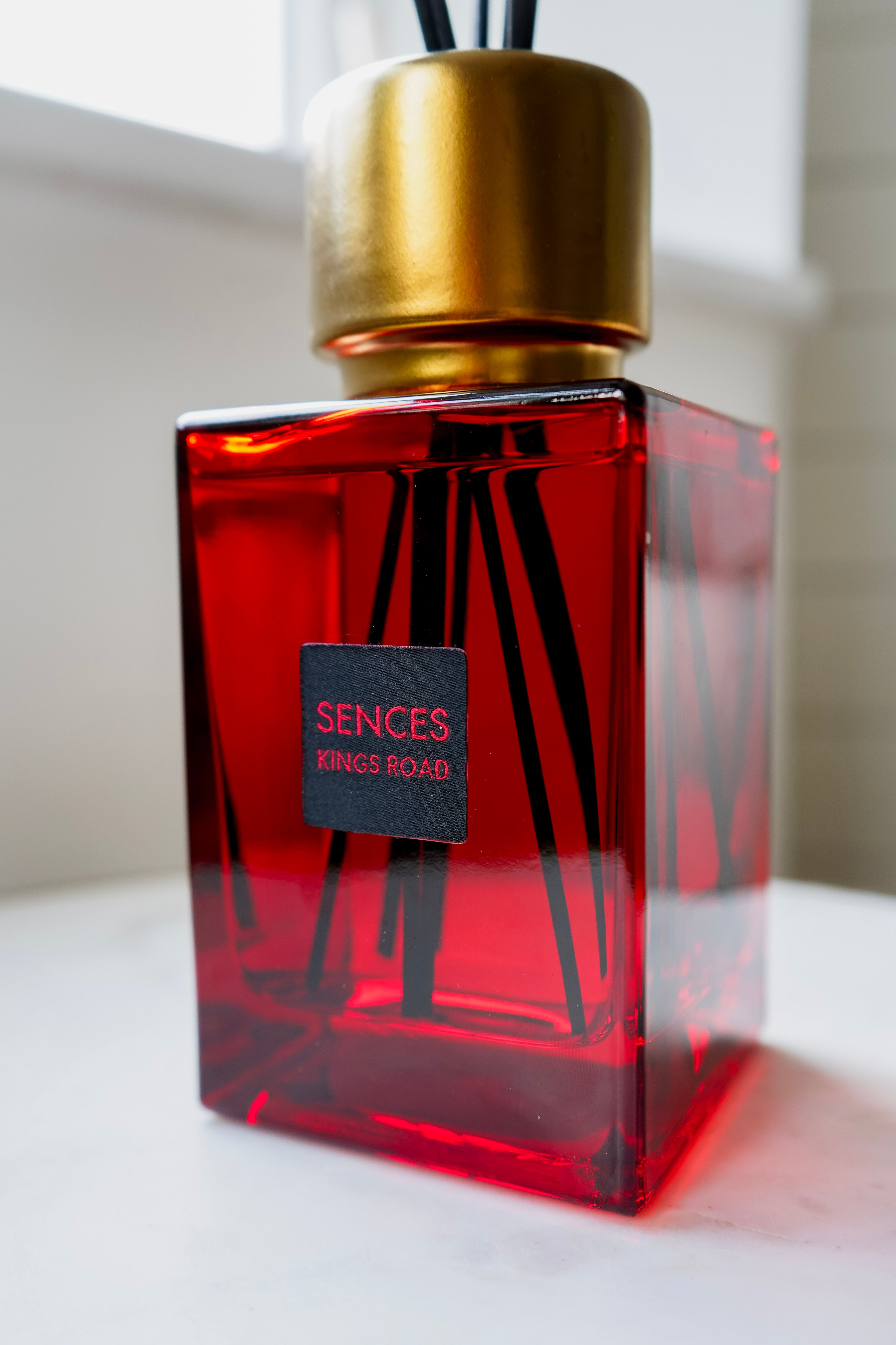 Red sences kings road diffuser bottle with gold cap on a white surface
