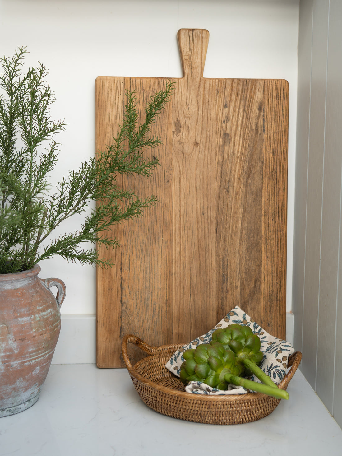 Wooden elm oversized cutting board with a plant and basket on a white surface