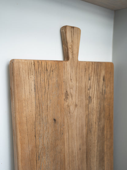Wooden elm oversized cutting board with a handle on a white wall