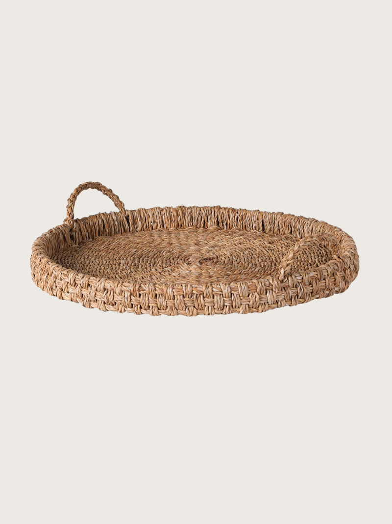 Round woven tray with handles on a light beige background