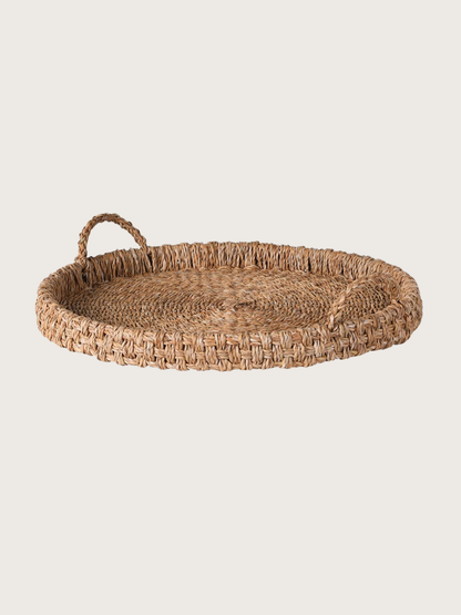 Round woven tray with handles on a light beige background