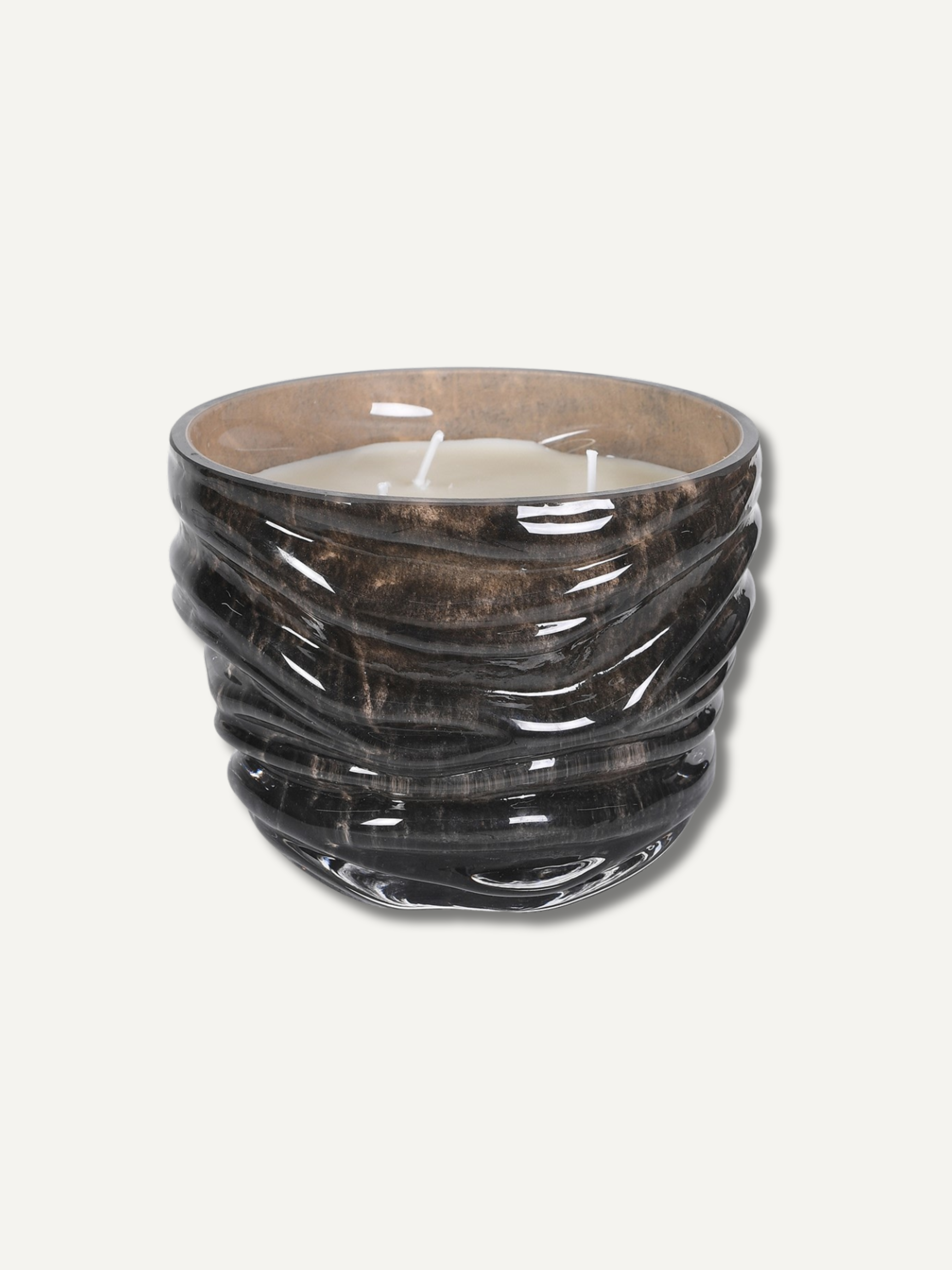 A dark brown and black textured glass candle holder with a wavy, ribbed design, containing a white wax candle, set against a plain off-white background.