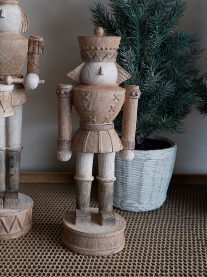 Wooden nutcracker figure in a home setting with a plant in the background