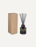 A reed diffuser bottle with black reeds next to its tan cardboard packaging box, set against a solid off-white background.