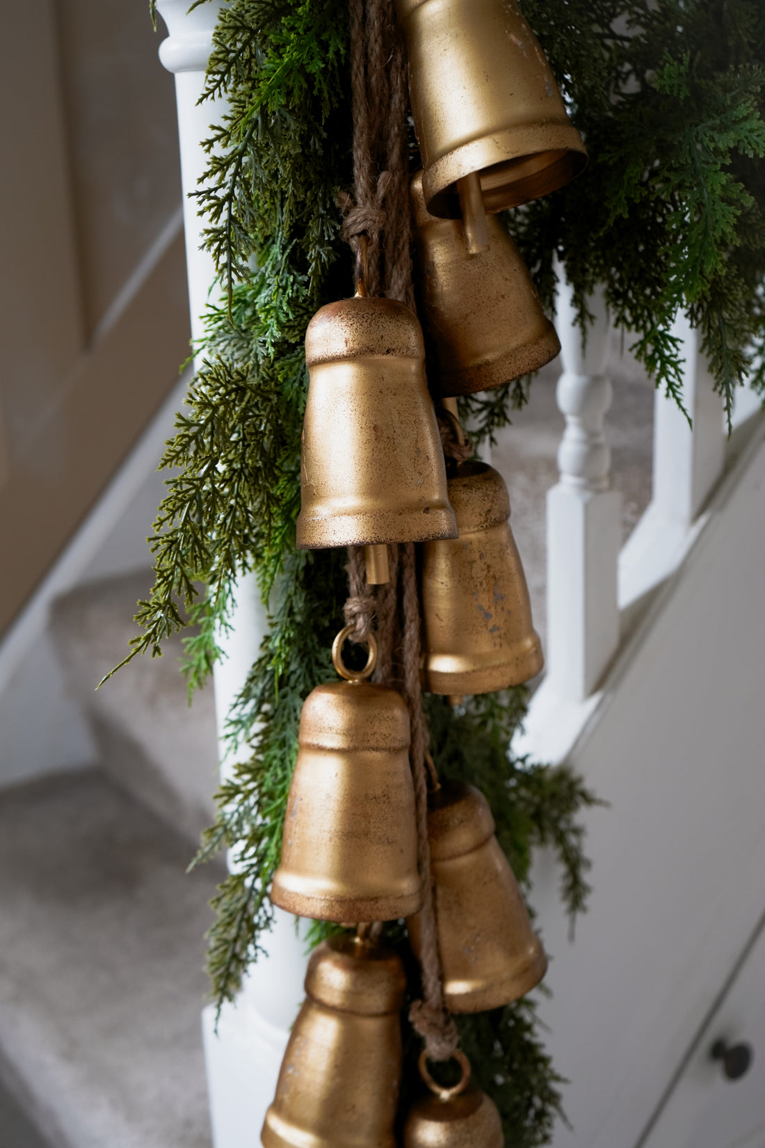 Decorative gold bells hanging on a white railing with greenery