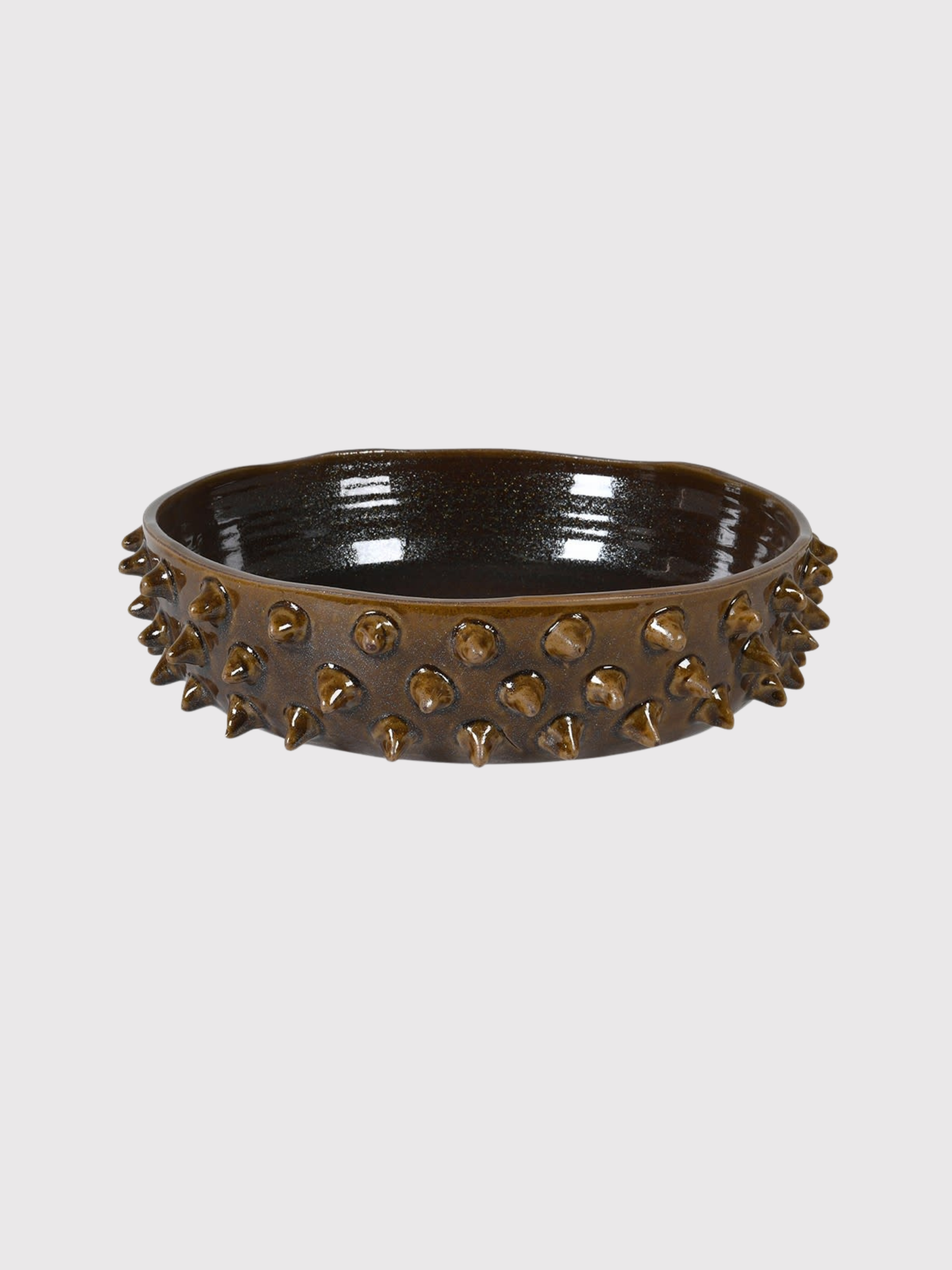 Decorative earth brown mahogany bowl with spike-like protrusions on a light gray background