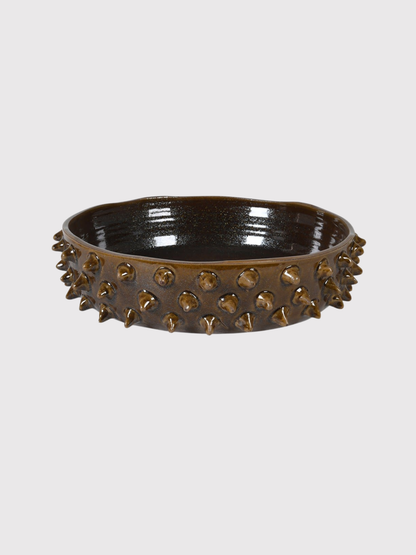 Decorative earth brown mahogany bowl with spike-like protrusions on a light gray background