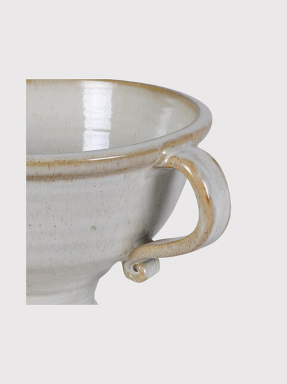 White ceramic urn vase with brown rim and handle on a light gray background