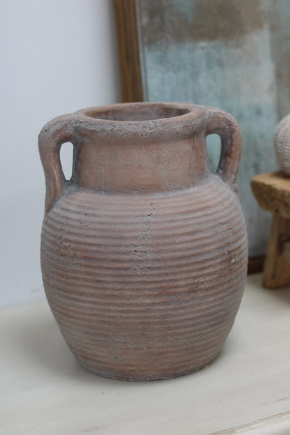 Terracotta vase with ribbed texture on a light surface
