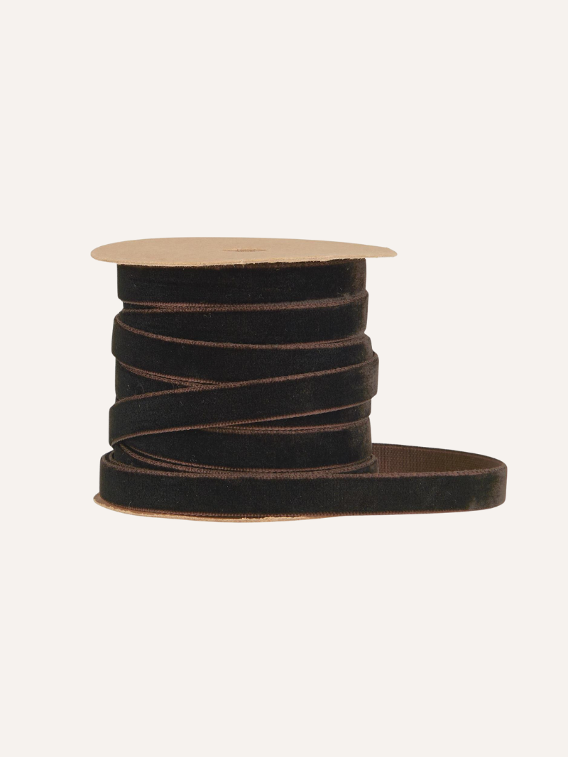 Spool of mocca brown velvet ribbon on a beige spool against a white background