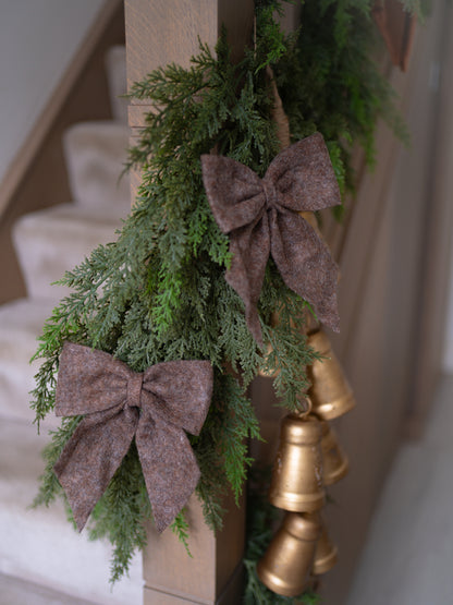 Decorative garland with brown bows and gold bells on a staircase.