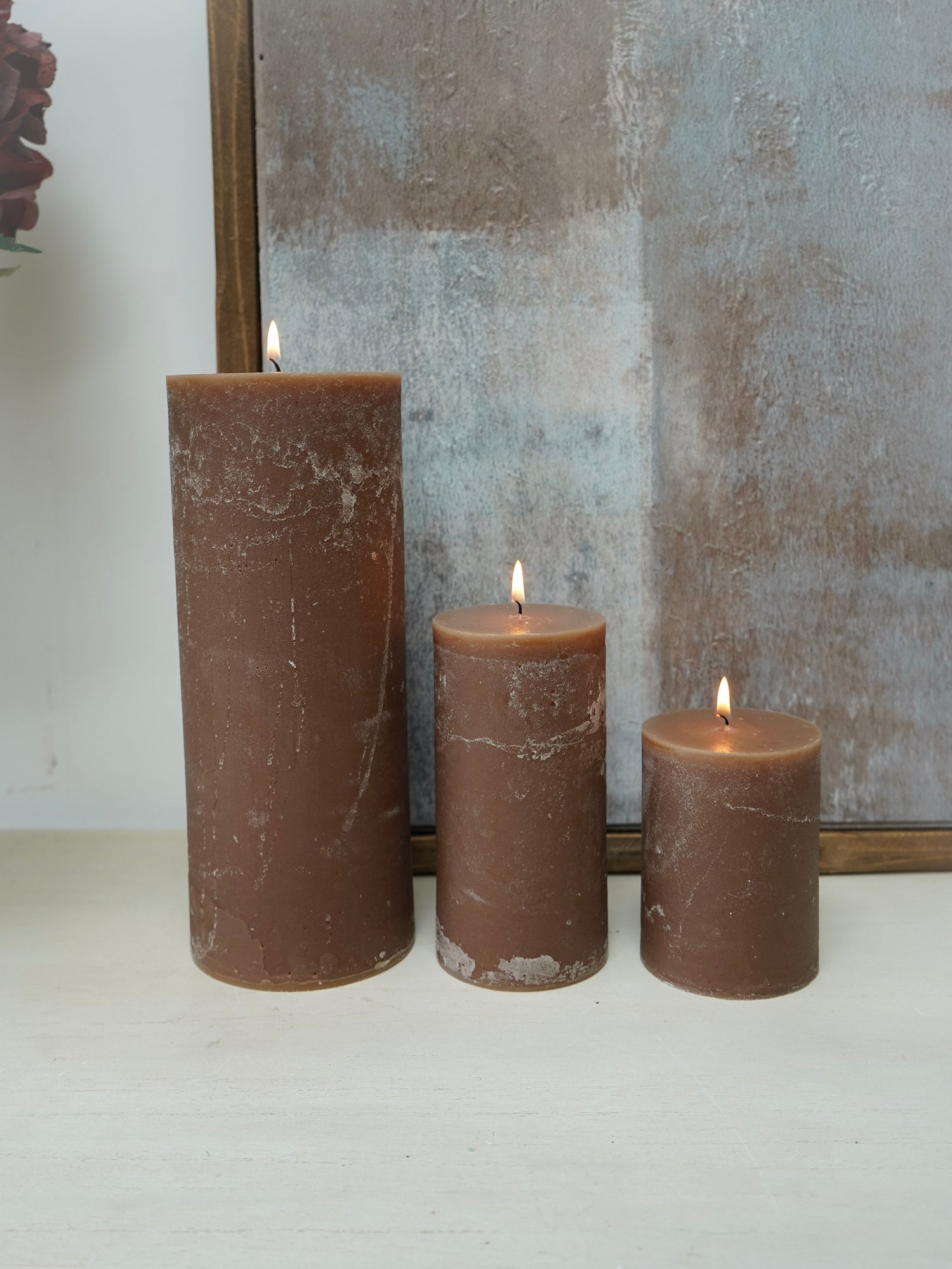 Three brown pillar  candles with a mirror in the background