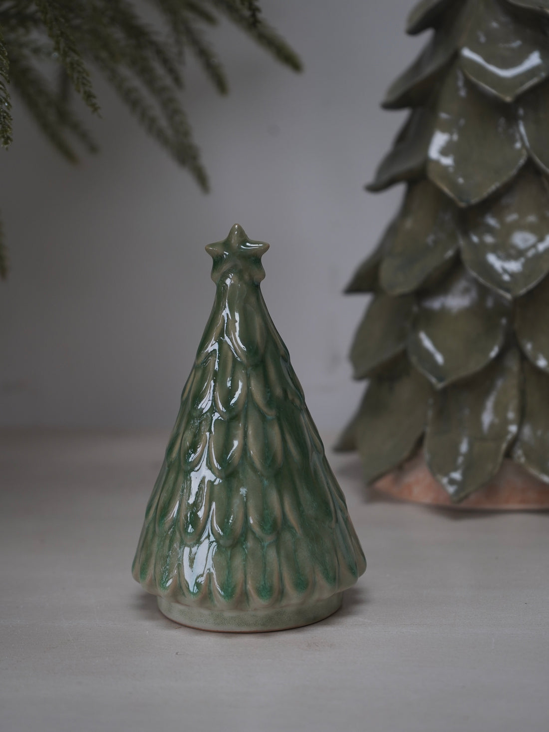 Green ceramic Christmas tree ornament on a neutral background