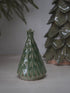 Green ceramic Christmas tree ornament on a neutral background
