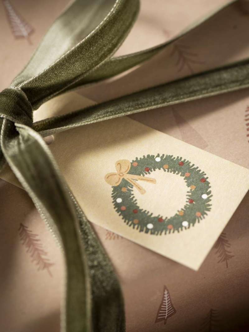 Gift wrapped in brown paper with a moss green velvet ribbon and a small card featuring a Christmas wreath design.