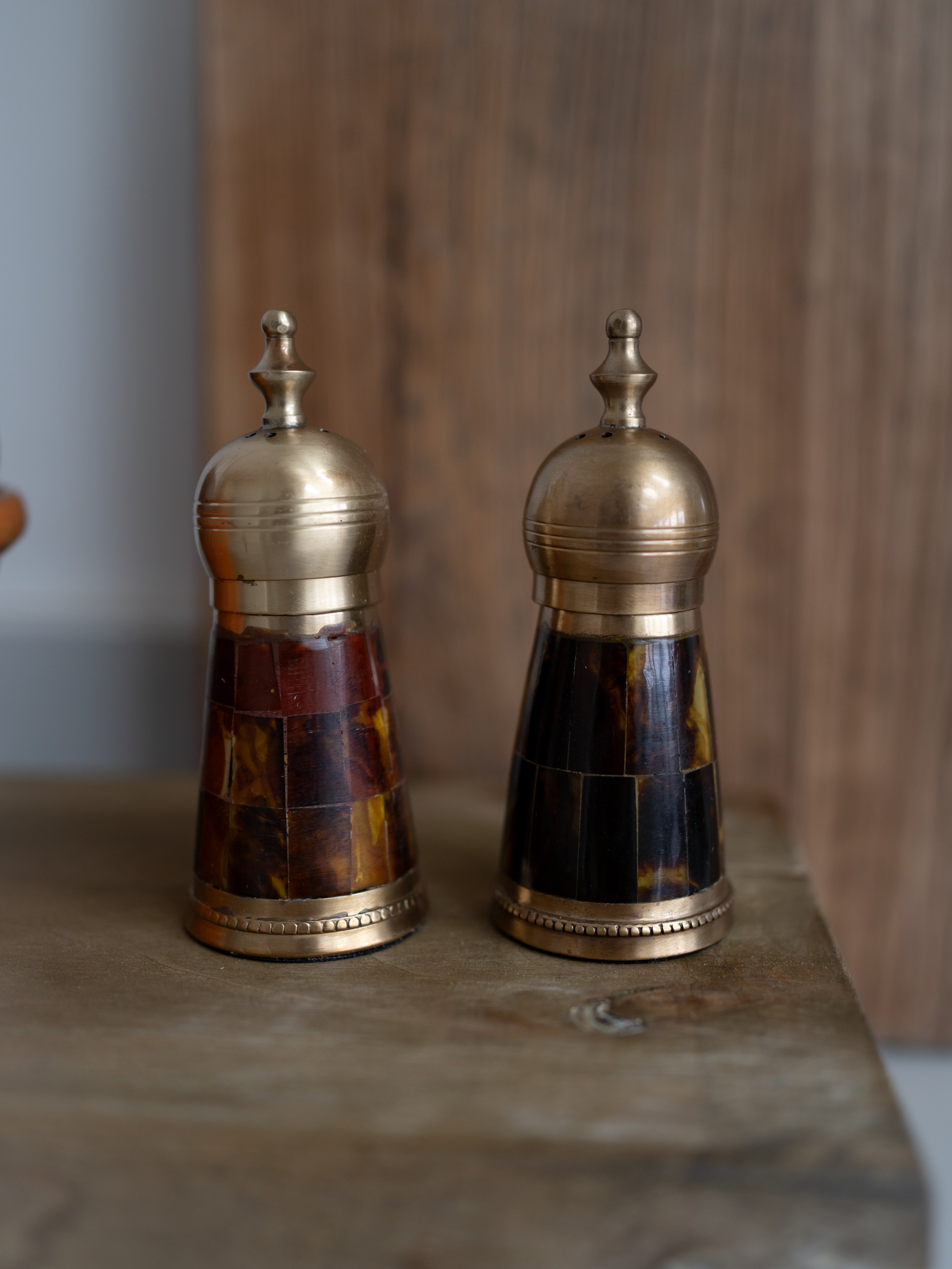 Two decorative salt and pepper shakers with mosaic designs on a wooden surface.
