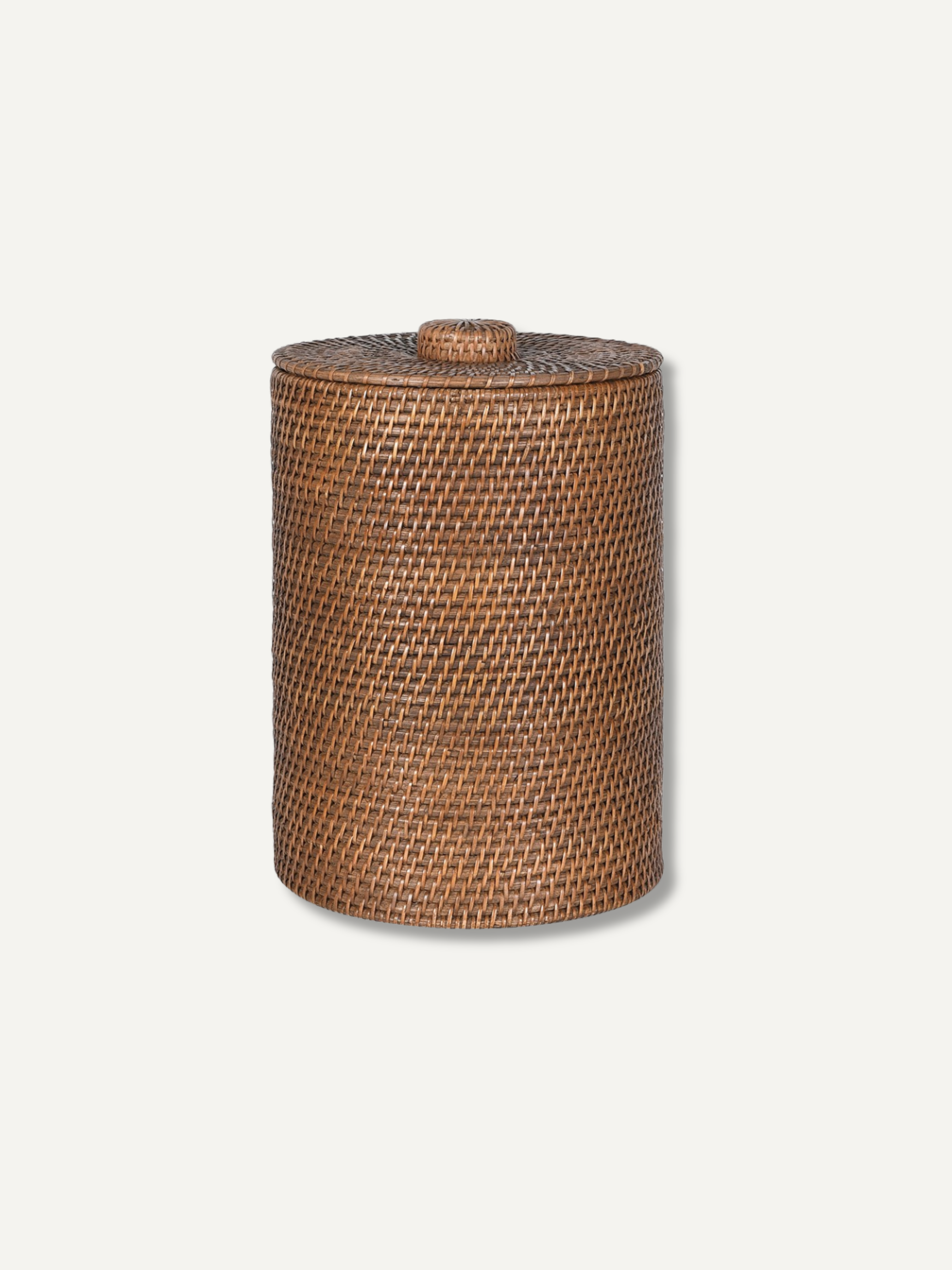 A cylindrical woven rattan storage basket with a matching lid and small top knob, shown on a plain light gray background.