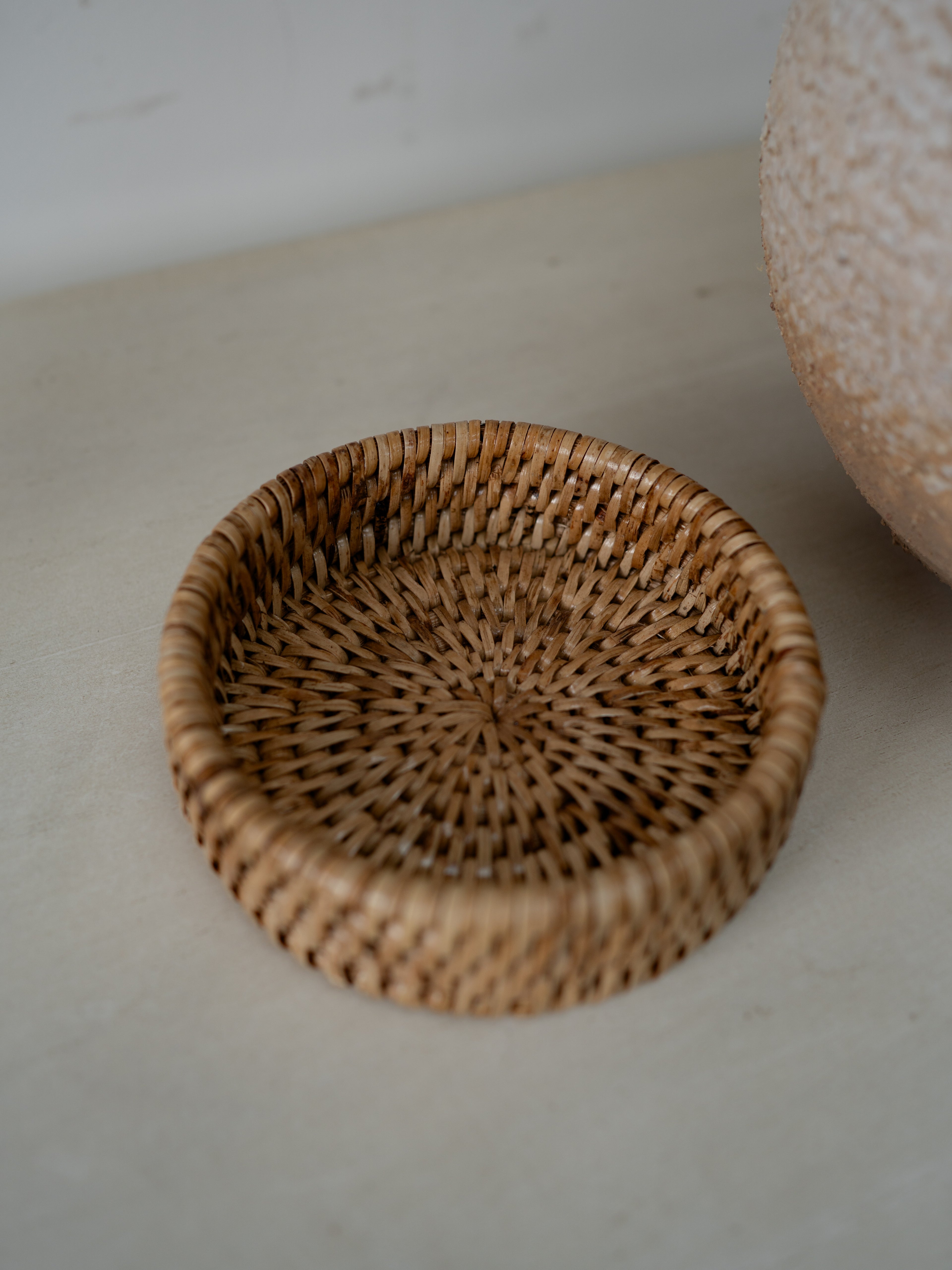 Woven coaster on a light surface with a neutral background