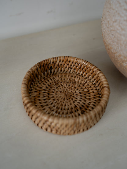 Woven coaster on a light surface with a neutral background