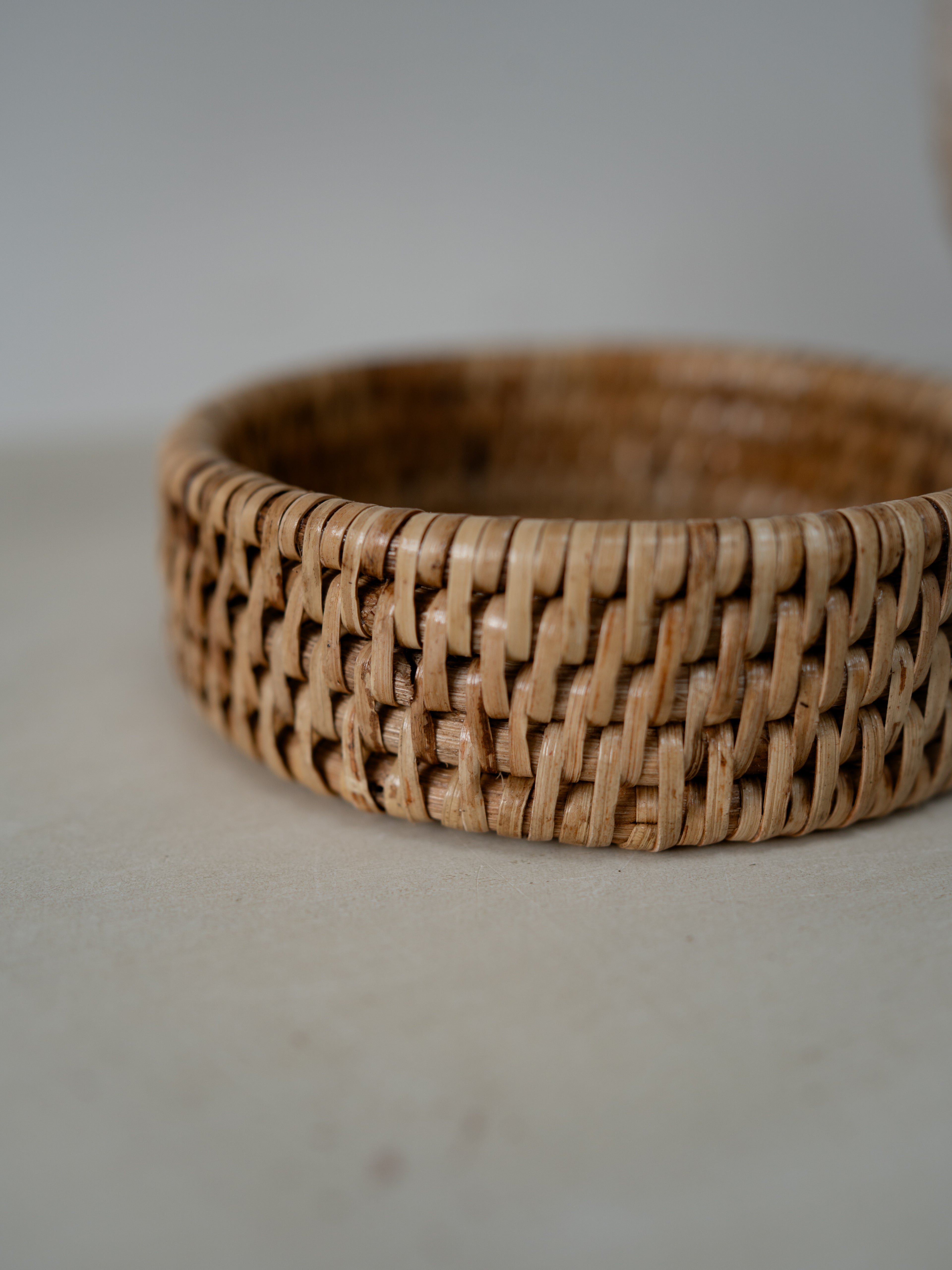 Woven rattan coaster on a plain background